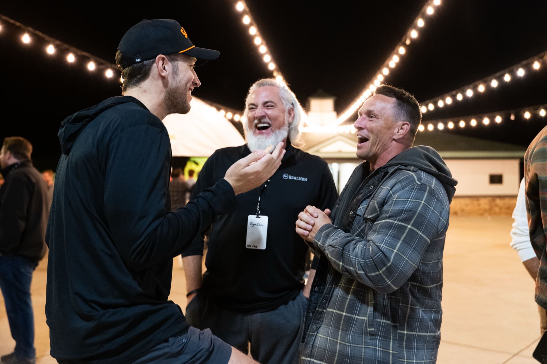 Men gathered in worship under the lights at a RealMen retreat